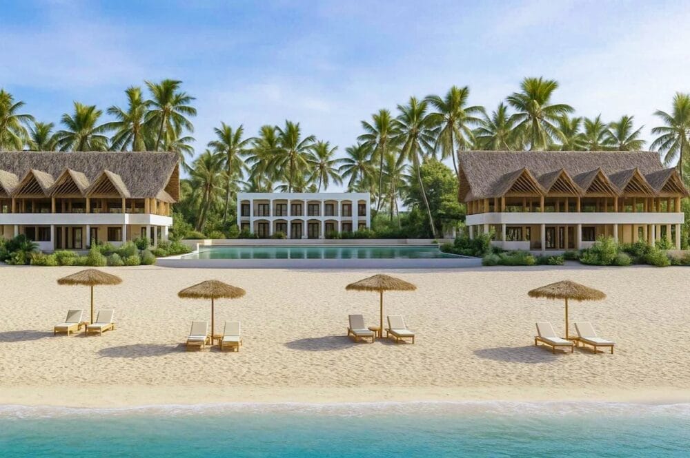Un resort tropicale sulla spiaggia in stile Seaclub con ville dai tetti di paglia, palme e lettini sotto ombrelloni di paglia sull'arenile di Nungwi Beach, di fronte a un mare turchese e a un edificio centrale bianco sullo sfondo.