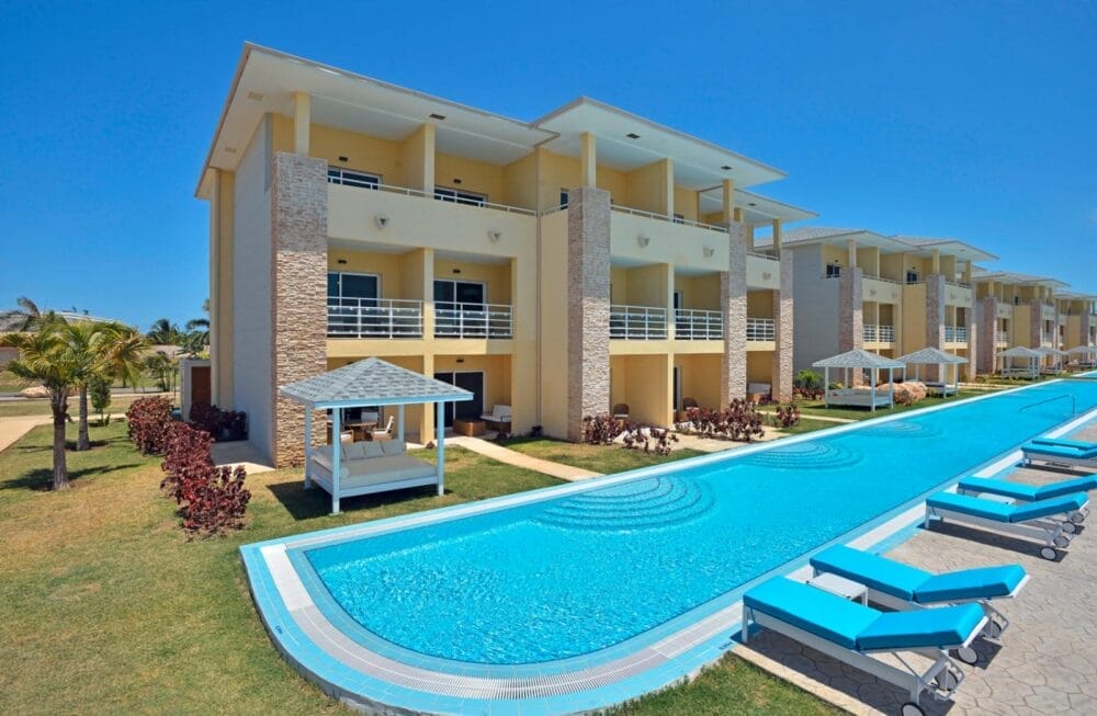 I moderni edifici gialli a tre piani del resort Paradisus Varadero, dotati di balconi, si affacciano su una lunga piscina blu fiancheggiata da sedie a sdraio turchesi e cabanas bianche. Palme ed erba circondano questo soleggiato rifugio termale di Varadero.