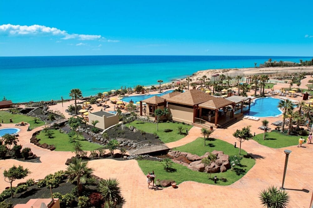 Il Veraclub Tindaya all inclusive di Fuerteventura dispone di piscine, palme, lettini e giardini lussureggianti che si affacciano su un oceano turchese sotto un cielo azzurro e limpido. Gli ospiti possono passeggiare e rilassarsi in questo paradiso tropicale.