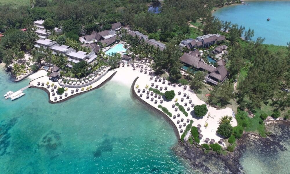 Vista aerea del Lagoon Attitude, uno splendido resort di Mauritius, caratterizzato da spiagge di sabbia bianca, acqua turchese, lettini, ombrelloni, palme ed edifici multipli circondati da una vegetazione lussureggiante.