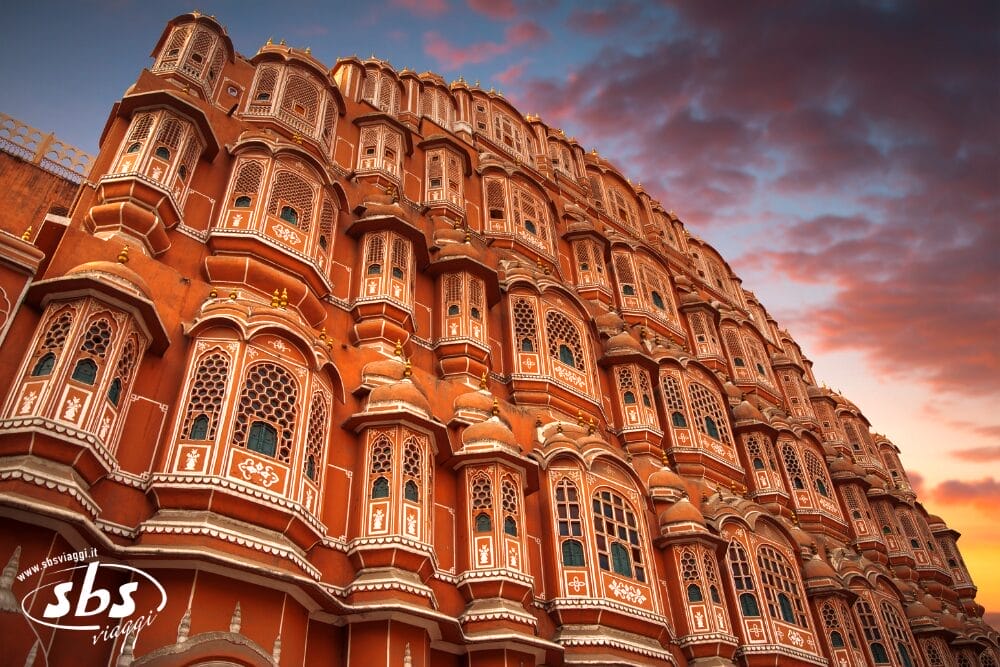 Una vista ravvicinata dell'ornato Hawa Mahal in arenaria rossa e rosa a Jaipur, in India Splendida, con numerose piccole finestre e intricati reticoli nel cielo colorato del tramonto.