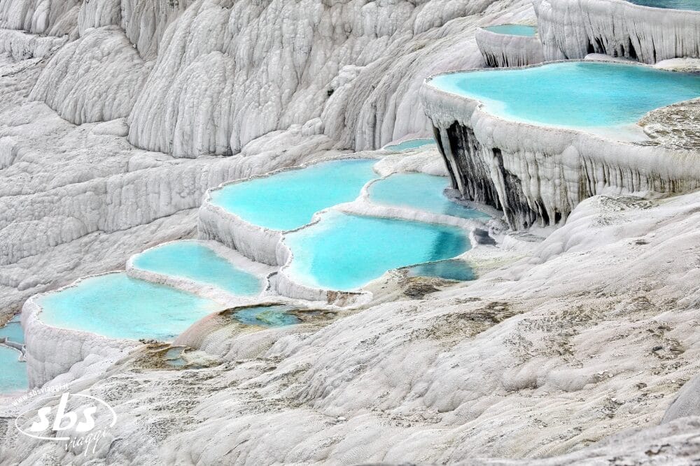 Un'acqua blu in una zona rocciosa con Pamukkale sullo sfondo, perfetta per la vostra avventura Grantour Turchia 2026.
