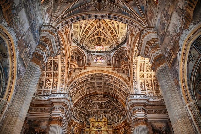 Guardare l'ornato soffitto interno di una grande cattedrale, con intagli dettagliati, archi, colonne, affreschi intricati e una vetrata che fa entrare la luce dall'alto: una bozza automatica di arte architettonica.