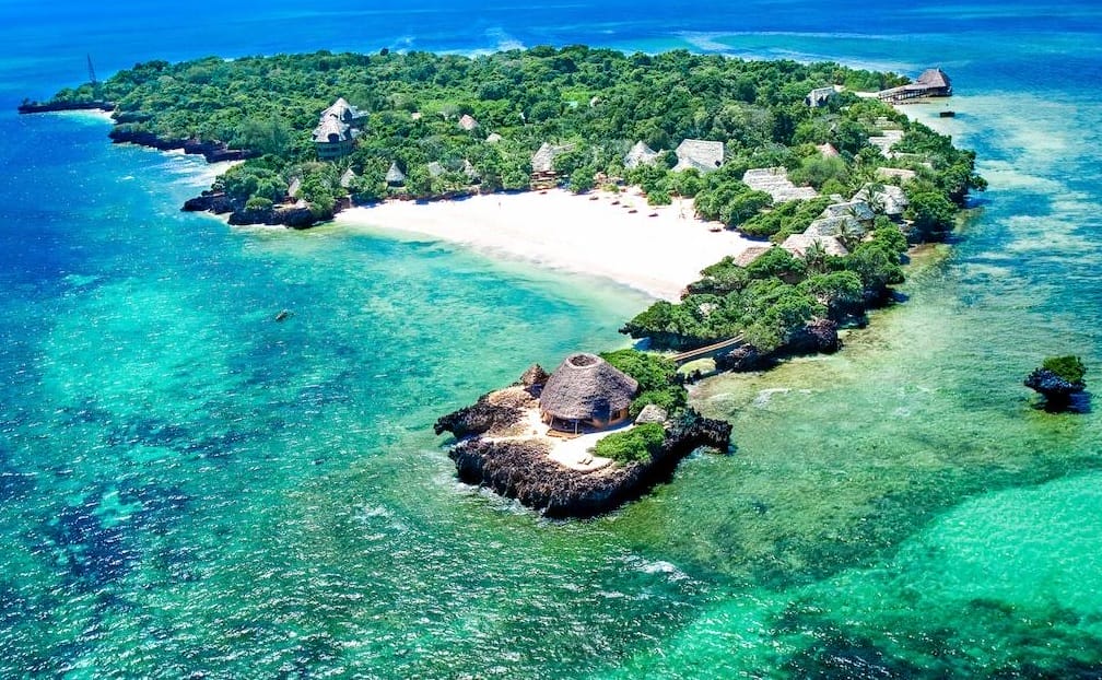 Veduta aerea dell'isola di Chale con la sua vegetazione lussureggiante, le spiagge di sabbia bianca, l'acqua turchese e le capanne e gli edifici con il tetto di paglia: qui si trova il Sands At Chale, un idilliaco hotel dell'isola di Chale circondato dall'oceano.
