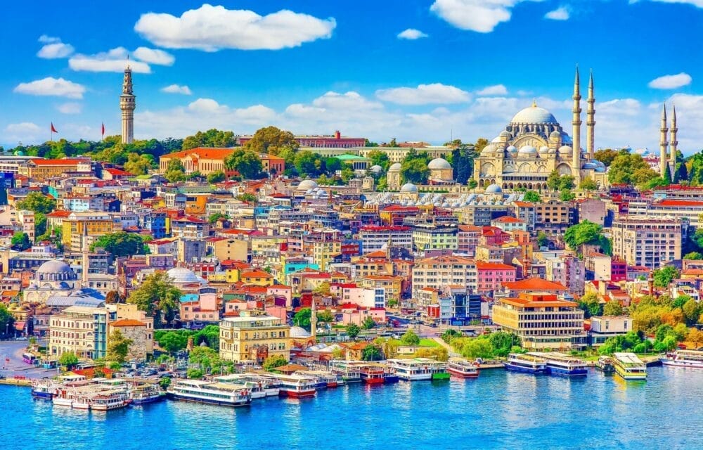 Colorato paesaggio urbano di Istanbul con molti edifici, barche sul lungomare e importanti moschee con cupole e minareti sotto un cielo blu brillante con nuvole soffici, catturato in un vibrante stile Bozza automatico.