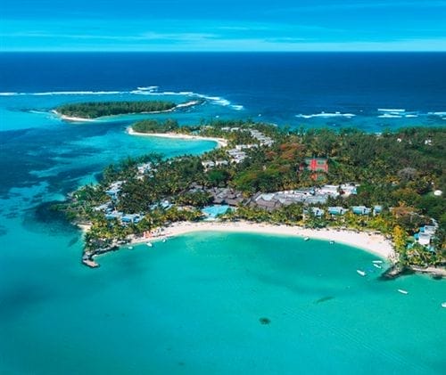 Veduta aerea di una costa tropicale con acque turchesi, spiagge sabbiose, alberi verdeggianti e piccole isole, con lo Shandrani Beachcomber Resort & Spa immerso tra le fronde sotto un cielo azzurro e limpido.