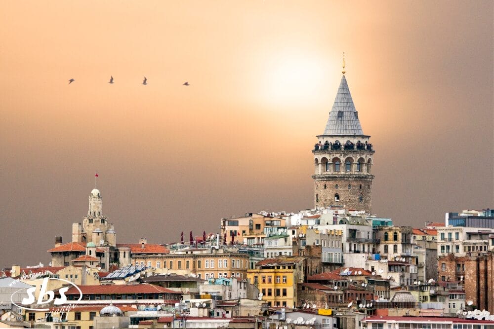 Un paesaggio urbano con la storica Torre di Galata che svetta su edifici colorati al tramonto, con un cielo arancione tenue e quattro uccelli che volano in formazione, cattura il fascino di Istanbul come in uno schizzo di Bozza.