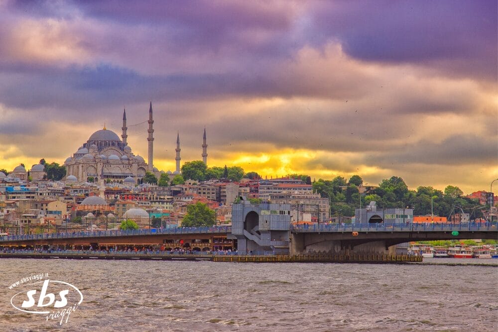 Vista dello skyline di Istanbul con la Moschea di Suleymaniye e i suoi minareti al tramonto, le nuvole vibranti in alto, il Ponte di Galata che attraversa l'acqua e gli edifici colorati della città: una scena indimenticabile catturata come una bozza automatica.