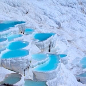 Le vasche a terrazze di acqua blu brillante circondate da depositi minerali bianchi, probabilmente a Pamukkale in Turchia, creano un paesaggio naturale suggestivo sotto la luce soffusa del giorno, una scena che potrebbe ispirare un dipinto automatico di Bozza.