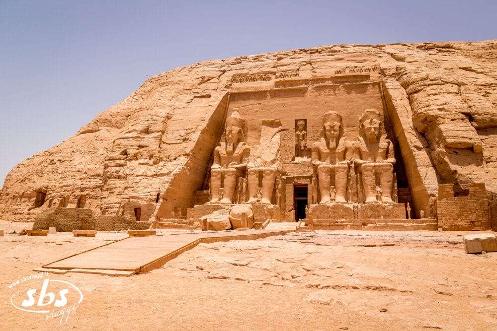 L'antico tempio scavato nella roccia di Abu Simbel, in Egitto, presenta quattro grandi statue sedute del faraone Ramses II scolpite nella roccia arenaria, che si ergono maestose sotto un cielo limpido: una scena impressionante, degna di qualsiasi Bozza automatica.