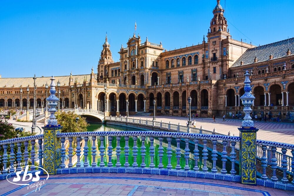 Una veduta di Plaza de España a Siviglia, in Spagna, con un grande edificio semicircolare, un canale con un ponte e una balaustra piastrellata in primo piano in una giornata di sole, perfetta da immortalare con la Bozza automatica.