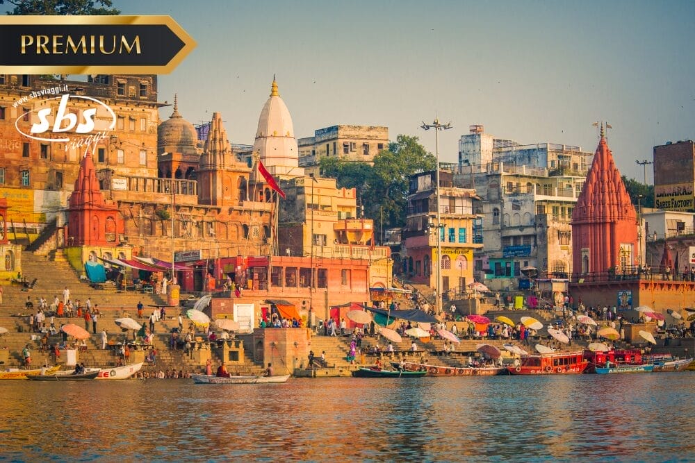 Una vivace veduta fluviale di Varanasi, in India, rivela antichi edifici colorati, templi e scalinate affollate di persone lungo le rive del fiume Gange sotto un cielo limpido: una Bozza vivente automatica di una tradizione senza tempo.