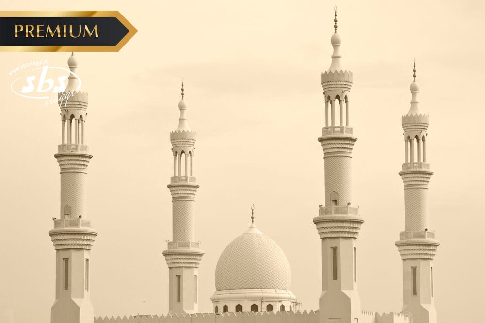 Immagine in tonalità seppia di una moschea con quattro alti minareti e una grande cupola centrale; nell'angolo in alto a sinistra compare l'etichetta "PREMIUM" e in basso a destra la scritta "Bozza automatica".