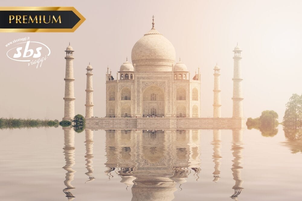 Il Taj Mahal si riflette nell'acqua calma sotto un cielo velato. Nell'angolo in alto a sinistra compaiono il banner "PREMIUM" in oro, il logo ovale "sbs viaggi" e la frase "Bozza automatica".