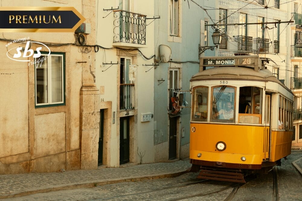 Un classico tram giallo viaggia su binari acciottolati in una strada stretta fiancheggiata da vecchi edifici color pastello a Lisbona, in Portogallo. I cartelli "PREMIUM", "sbs" e "Bozza automatica" sono visibili nell'angolo in alto a sinistra.
