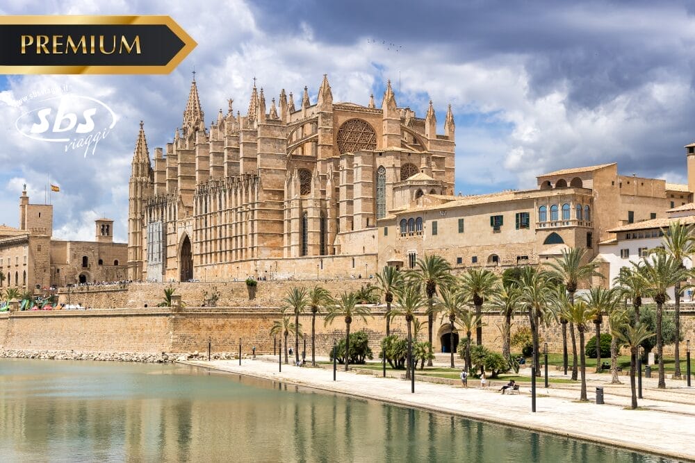 Cattedrale in stile gotico con dettagli intricati, palme e una piscina riflettente di fronte a un cielo parzialmente nuvoloso, che evoca il fascino senza tempo di Toledo. I loghi "PREMIUM" e "SBS Viaggi" sono riportati nell'angolo in alto a sinistra.
