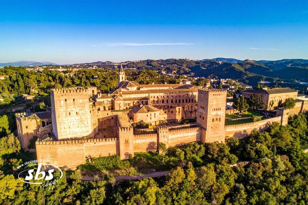 Veduta aerea dell'Alhambra, un grande palazzo storico e un complesso di fortezze immerso nel verde, circondato da colline sotto un cielo azzurro e limpido a Granada, in Spagna: una Bozza automatica di straordinaria bellezza architettonica.