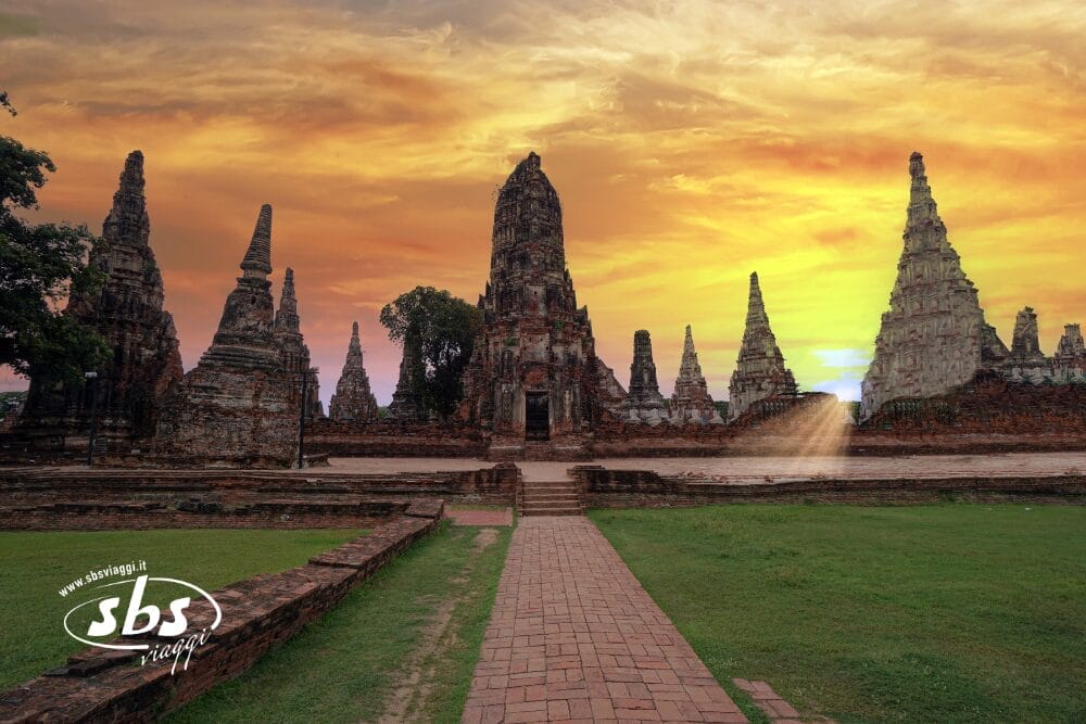 Antiche rovine di templi con alte guglie e vialetti in mattoni al tramonto, sotto un cielo colorato con la luce dorata che filtra attraverso un arco: una bozza automatica di storia incisa in ogni pietra.