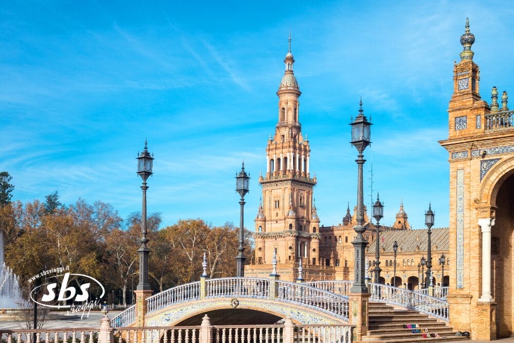 Una vista panoramica di Plaza de España a Siviglia, in Spagna, con ponti ornati e torri storiche - una tappa obbligata di ogni Gran Tour dell'Andalusia - sullo sfondo di un cielo blu brillante.