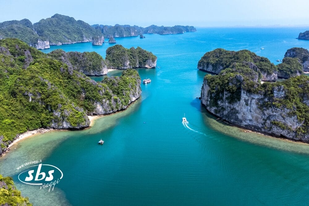 Veduta aerea di una baia turchese con isole calcaree verdeggianti e barche che navigano tra di loro sotto un cielo azzurro e limpido. La tranquilla scena tropicale è caratterizzata da acque calme, scogliere boscose e cattura una vera Bozza automatica della bellezza della natura.