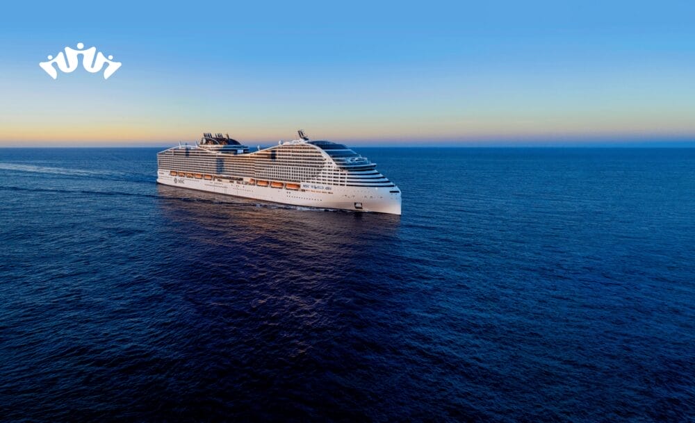 Una grande nave da crociera bianca MSC World Asia naviga sulle calme acque blu dell'oceano sotto un cielo limpido al tramonto, promuovendo un'indimenticabile crociera mediterranea. Un piccolo logo appare nell'angolo in alto a sinistra dell'immagine.